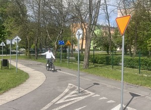 rowerzysta w miasteczku rowerowym przygotowujący się do skrętu na drodze postawione sa znaki drogowe