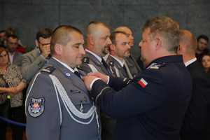 komendant gratuluje medalu policjantowi