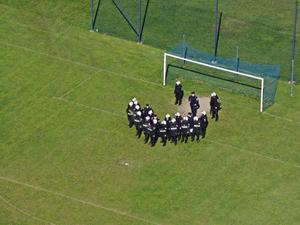 Pododdział policji ćwiczy na boisku sportowymn ustawienia w szyku