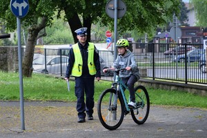 umundurowany policjant oraz rowerzysta podczas jazdy po miasteczku rowerowym