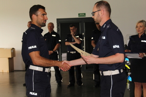 Policjant gratuluje innemu policjantowi i trzyma w ręku dyplom