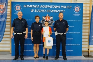9. chłopiec z nagrodami stojący z policjantami