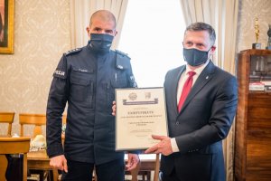 Komendant wojewódzki policji w Krakowie przekazuje certyfikat rektorowi uczelni