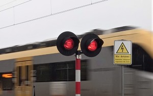 sygnalizator nadający światło czerwone w tle przejeżdżający pociąg