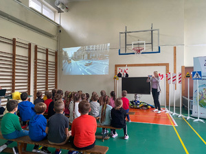 dzieci w sali gimnastycznej oglądają film edukacyjny o zasadach ruchu drogowego