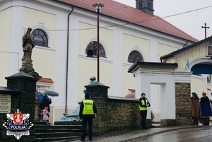 policjanci stojący z odblaskamu przy bramie wejściowej na teren kościoła w Makowie Podhalańskim