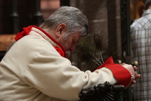 mężczyzna modlący się w historycznym stroju krakowiaka