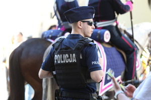 policjant pilnujący bezpieczeństwa naprzeciwko rekonstruktora na koniu