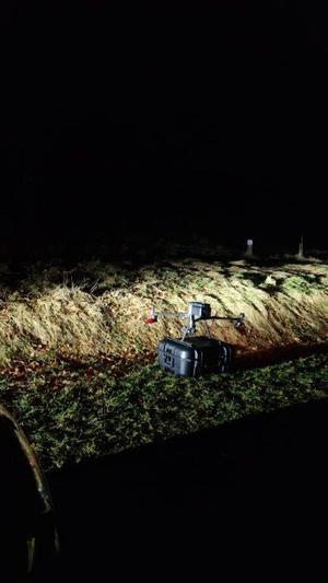 Oświetlony dron w nocy stojący na trawie w czasie działań poszukiwawczych