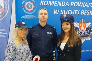 Pozujące do zdjęcia dwie panie w czapkach policyjnych  z policjantem