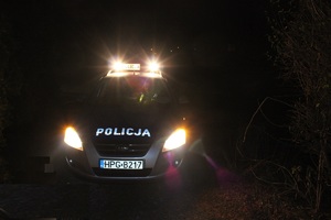 Policyjny radiowóz z włączonymi sygnałami,  w nocy
