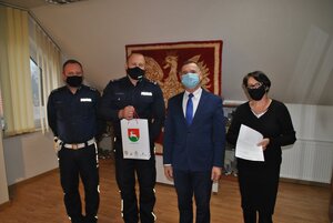 Komendant Powiatowy Policji w Brzesku trzymający w rękach urządzenie iBlow w towarzystwie osób uczestniczących w uroczystym przekazaniu