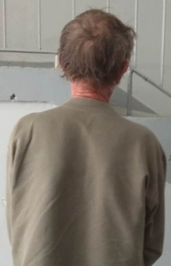 zatrzymany mężczyzna ubrany w bluzę koloru jasnego stojący tyłem