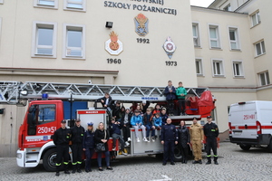 wóz strażacki z dziecmi oraz prowadzącymi zajecia policjantami i strażakami