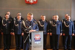 Stojący za pulpitem Komendant Wojewódzki Policji w Krakowie. Za nim w dwuszeregu umundurowani policjanci.