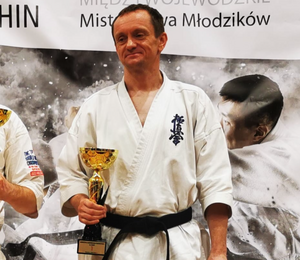 policjant ubrany w kimono z czarnym pasem podczas Mistrzostw Makroregionu Południowego w rece trzyma puchar i dyplom