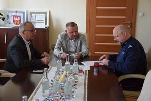 podpisanie porozumienia, przy stole umundurowany Komnednat Powiatowy po prawej stronie, na środu starosta dąbrowski, po lewej wicestraosta