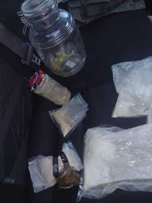 zabezpieczone narkotyki w foliowych opakowaniach oraz słoiku ułożone na siedzeniu w radiowozie