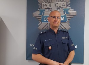 aspirant Łukasz Januszyk na tle logo oświęcimskiej Policji