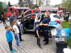 policjantka stoi przy radiowozie i przyierza czapkę dziecku