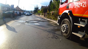 strażacy gaszą pożar, obok wóz bojowy, na chodniku ludzie obserwujący działania służb, w oddali policyjne radiowozy