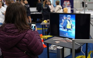 telewizor z wyświetlanymi materiałami promocyjnymi. Zainteresowana dziewczyna robi zdjęcie wyświetlanych treści