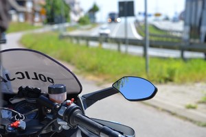 widok motocykla słuzbowego stojącego przy głownej trasie