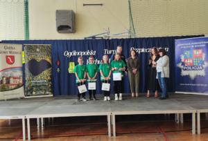 Organizatorzy turnieju, umundurowany policjant oraz uczniowie i opiekujowie z pucharem