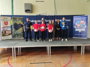 Umundurowani policjanci, uczestnicy turnieju, opiekun z pucharem oraz organizatorzy