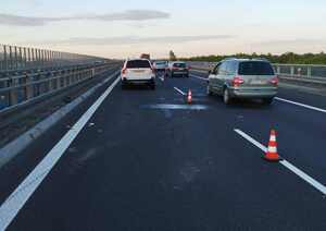biało volvo stojace na lewym pasie ruchu autostrady, pas wyłączony pachołkami i ruch innych pojazdów prawym pasem