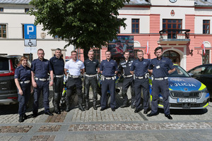 Policjanci Wydziału Ruchu Drogowego przy radiowozie. W tle budynek Urzędu Miasta i Gminy w Olkuszu.