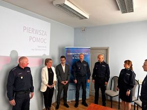 Policjanci oraz przedstawiciele władzy  opieki społecznej podczas otwarcia szkolenia na sali odpraw w Komisariacie Policji w Wolbromiu. W tle slajd prezentacji