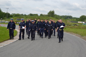 Policjanci idą po torze jazdy samochodem podczas odprawy