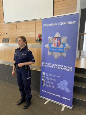 umundurowana policjantka stojąca przy rolapie z napisem Komenda Powiatowa policji w Chrzanowie