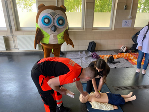 dziewczynka ćwicząca na fantomie uciskanie klatki piersiowej w obecności ratownika medycznego