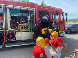 strażacy pokazujący przedszkolakom wóz strażacki