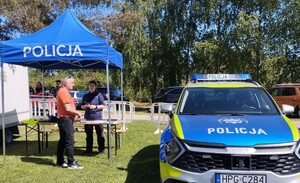 Piknik charytatywny na Jacusia 12.05 (6) policjantka na stoisku obok senior przy stoisku radiowóz