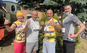 na tle drzewa i lokomotywy stoją policjanci w stroju cywilnym po udziale w biegach