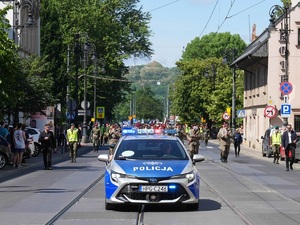 Na zdjeciu widać policyjny radiowóz  na czele pochodu wojskowego