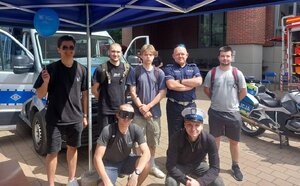 uczestnicy Festiwalu Nauki i Sztuki wraz z policjantem przy radiowozie i policyjnym motocyklu