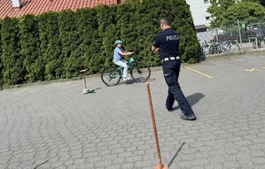uczennica pokonuje tor przeszkód podczas egzaminu na kartę rowerową obok stoi policjant
