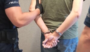 Zatrzymany w kajdankach obok  policjant przykład