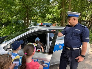 policjant pokazujący  dzieciom radiowóz