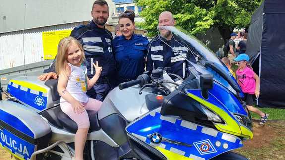 policjanci i policjantka przy motorze na motorze siedzi dziewczynka