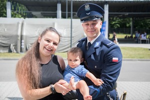 policjant w mundurze galowym i kobieta z małym dzieckiem