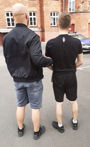 nieumundurowany policjant prowadzący zatrzymanego mężczyznę