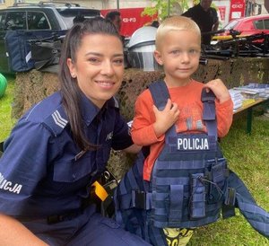 Policjantka pozuje z chłopcem ubranym w kamizelkę policyjną
