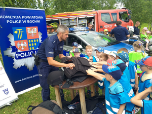 Umundurowani policjanci oraz dzieci oglądające policyjny sprzęt