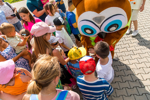 Maskotka stoi pośród dzieci uczestniczących w pikniku