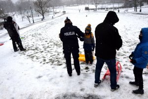 4 policjantka wręcza dziecku opaskę odblaskową na jednej ośnieżonych górek w parku